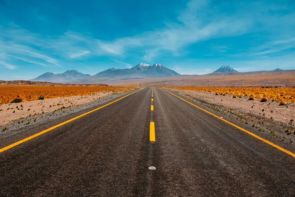 a desert road with mountains in the distance